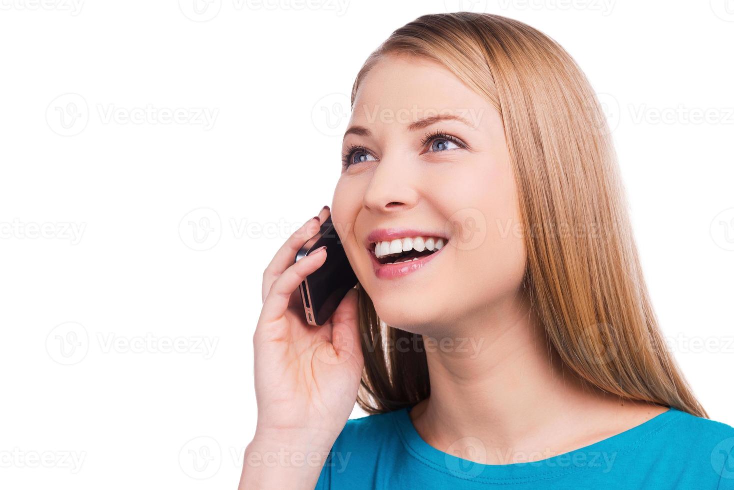 Great news Happy young women talking on the mobile phone and smiling while standing against white background photo