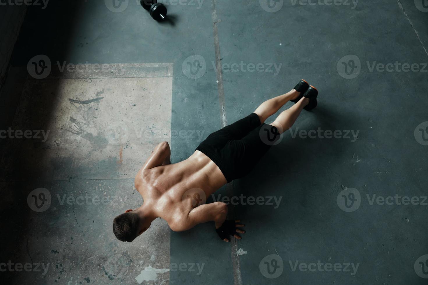 Top view of young muscular man doing push-up exercises in gym photo