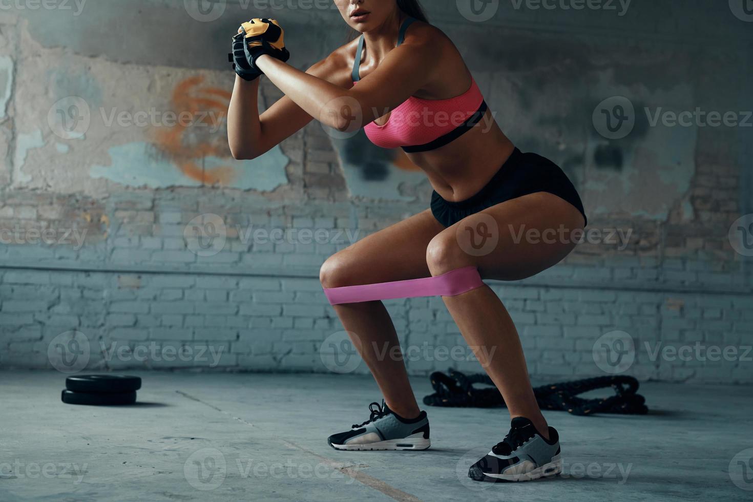 Unrecognizable woman using elastic resistance band while exercising in gym photo
