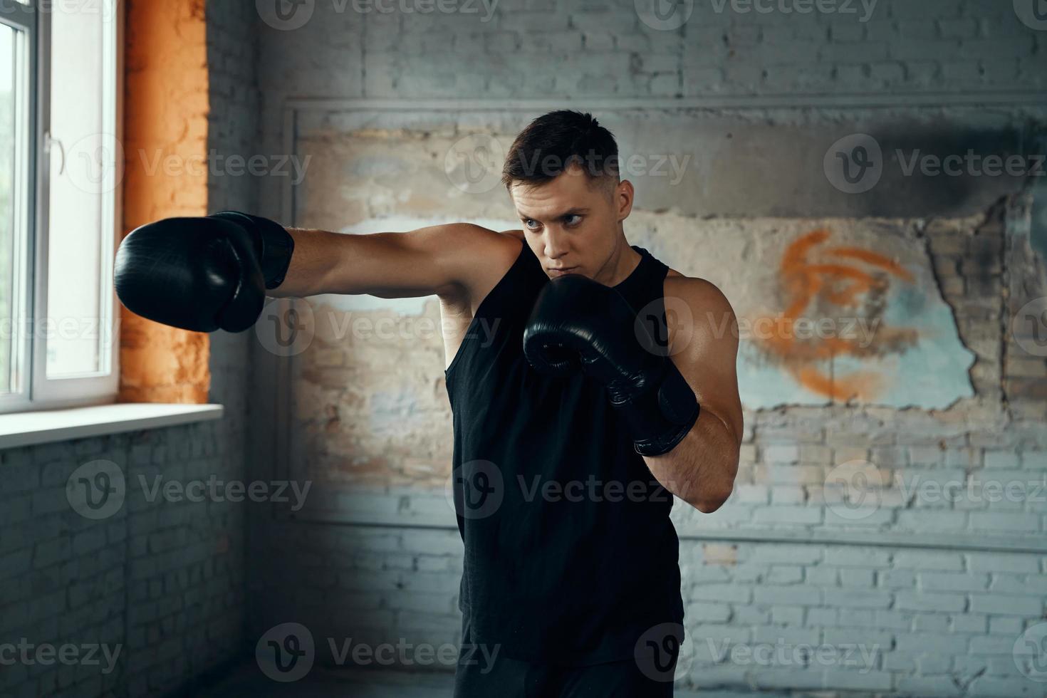 Confident young man practicing in punching while standing in gym photo