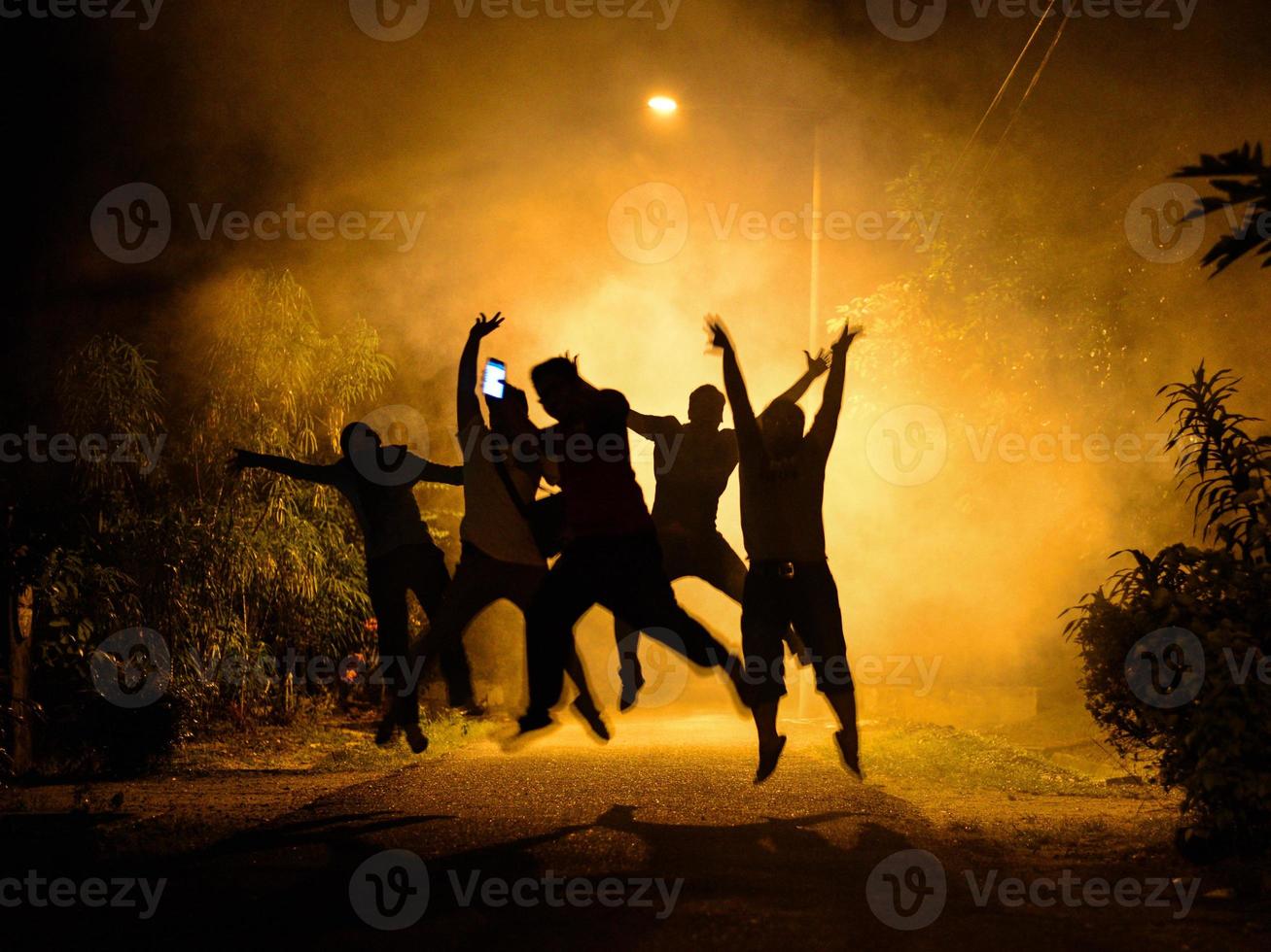 Youth group doing a jumping joy in a fireworks smoke against street lights photo