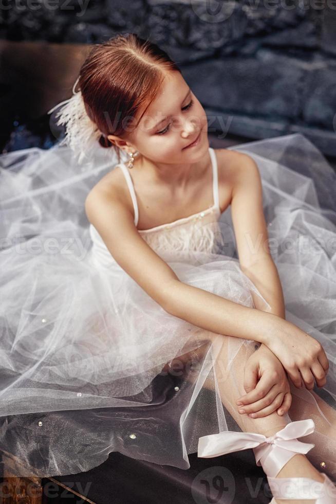 Girl in a white ball gown and shoes, beautiful red hair. Young theater actress photo