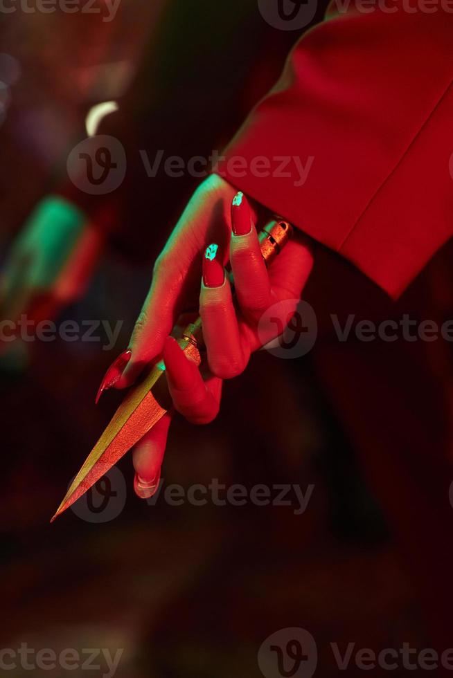 Anime woman in a red suit with short hair cut, black hair. A killer girl in a red jacket with a dagger in her hand. Beauty portrait photo