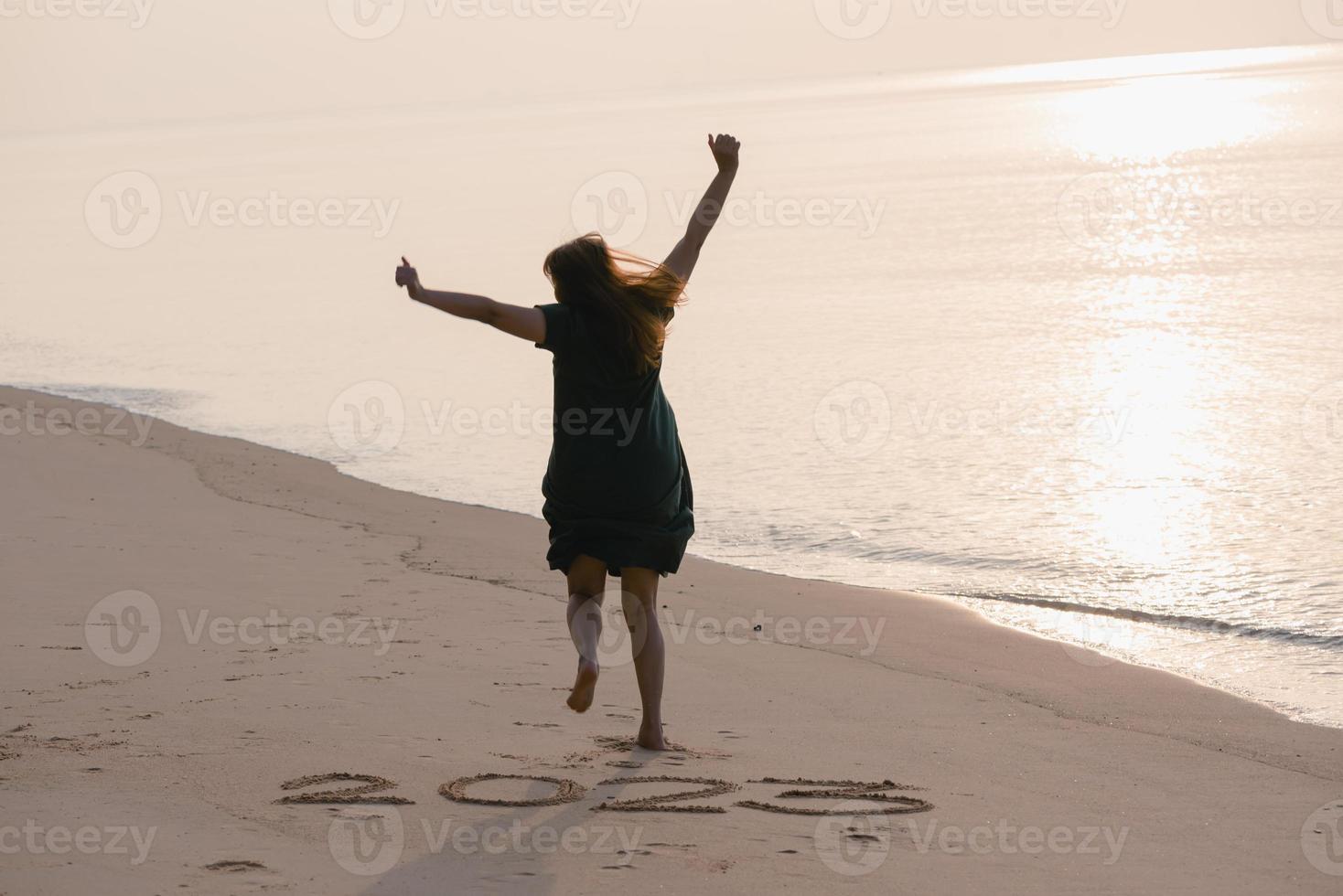 2023 Happy New Year, Young healthy woman running and jumping on the beach at sunrise, health care, health insurance, healthy life concept, copy space for banner. photo