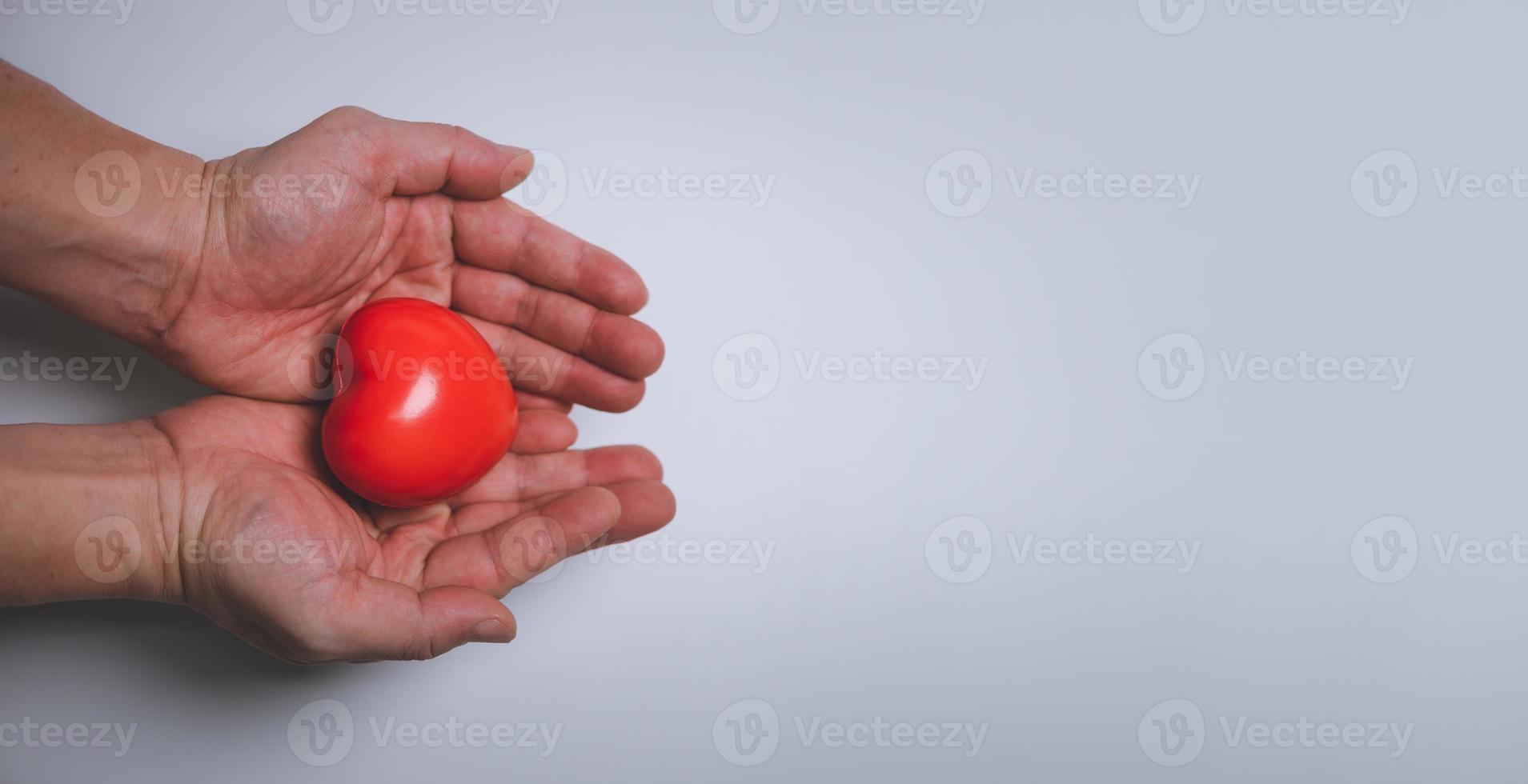 Hands holding and giving red heart for love, health care, organ donation, world heart day, world health day, mindfulness, well being, family insurance concept, copy space. photo