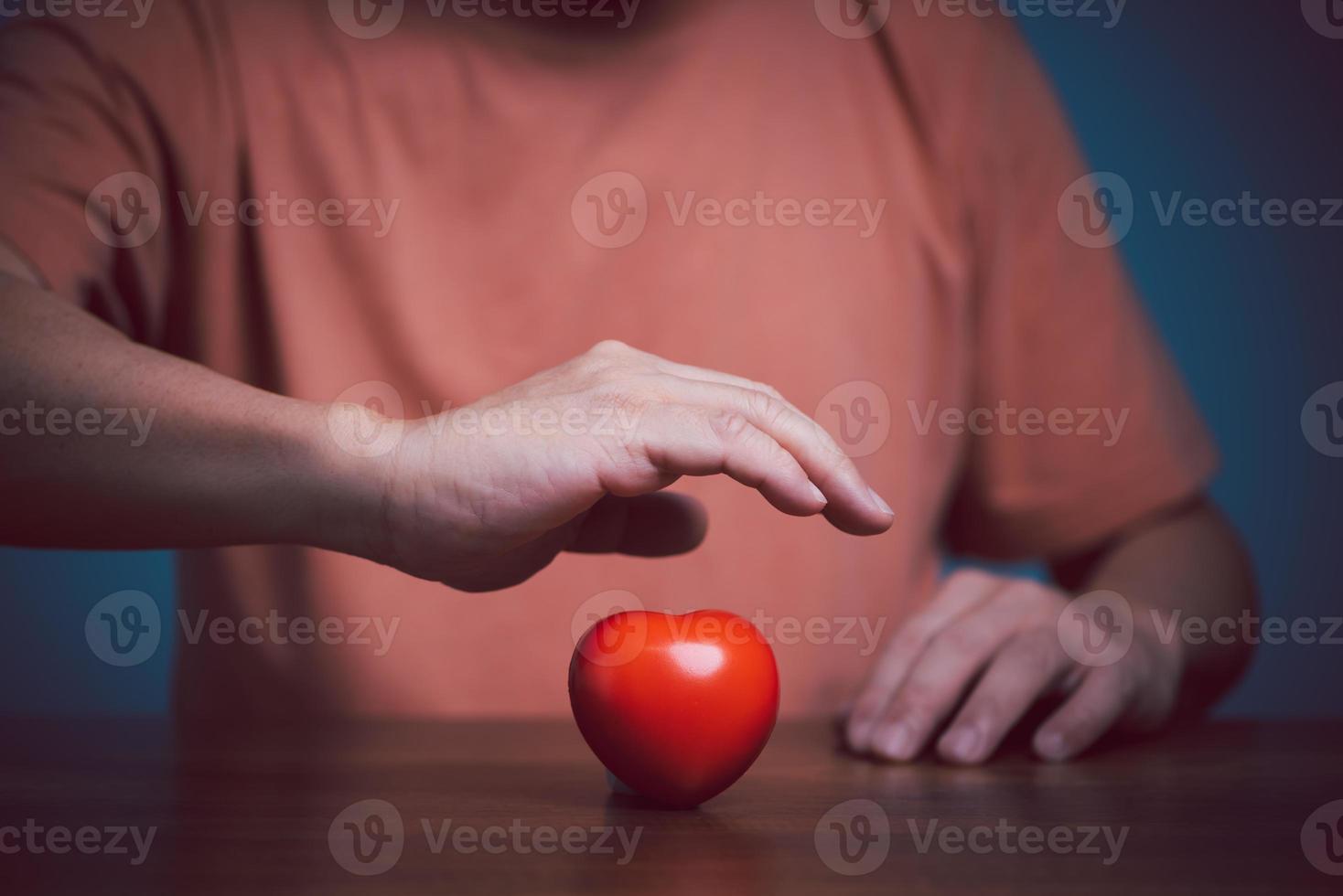 Hands holding and protect red heart for love, health care, organ donation, world heart day, world health day, mindfulness, well being, family insurance concept. photo