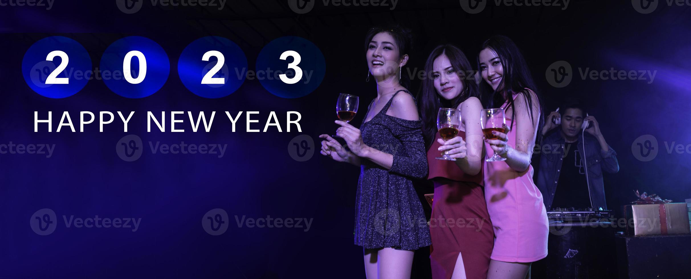 Happy new year 2023 celebration concept, Traveler people holding glasses of wine together with enjoying, dancing at colorful night party club. photo