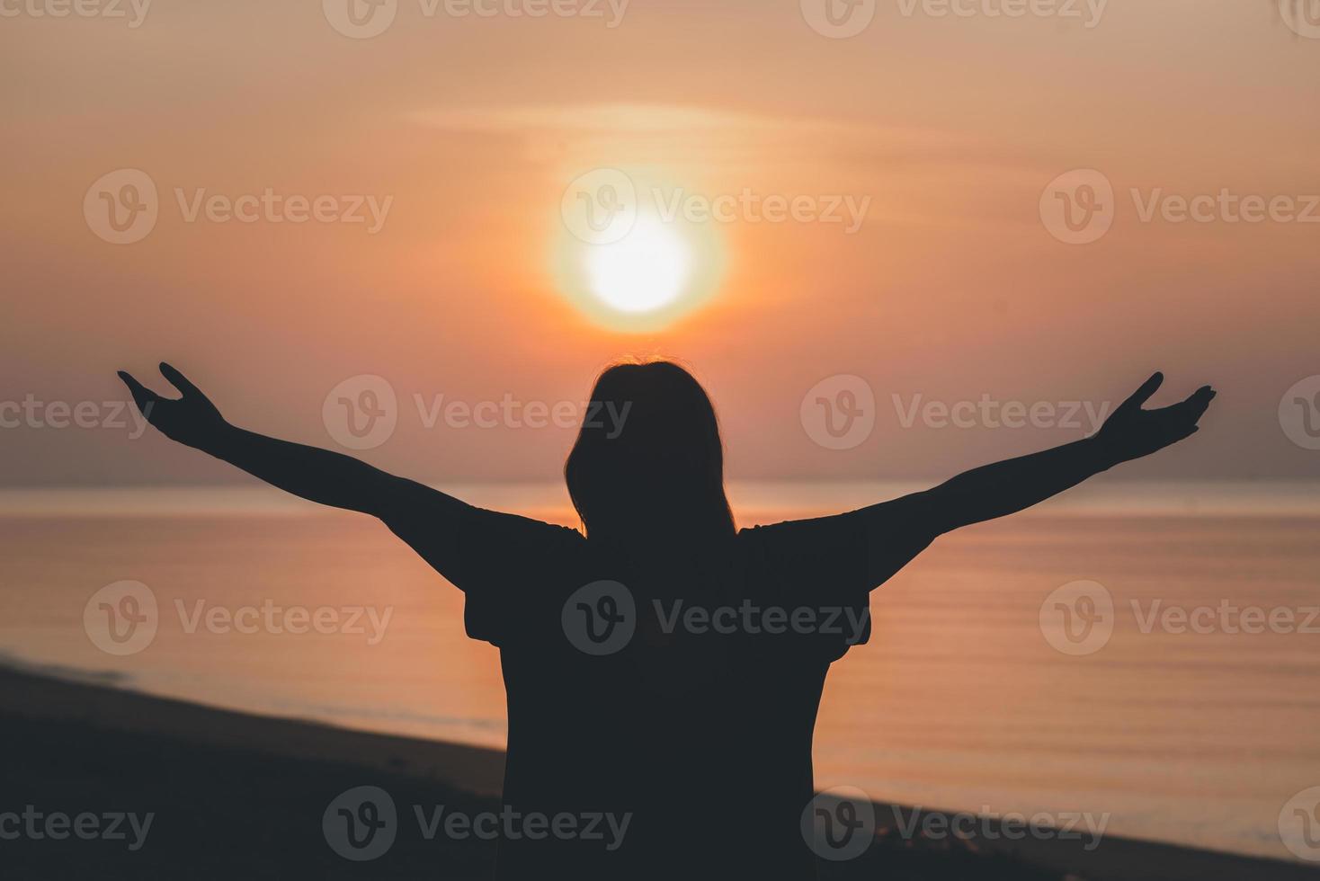 Silhouette of praying hands with God facing the sky at sunrise morning on the beach, Faith in religion and belief in God, Power of hope or love and devotion. photo