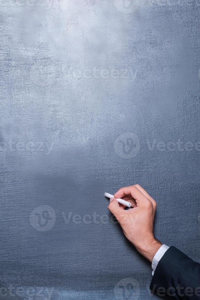 Drawing on the blackboard. Close-up of man writing on the blackboard by chalk photo