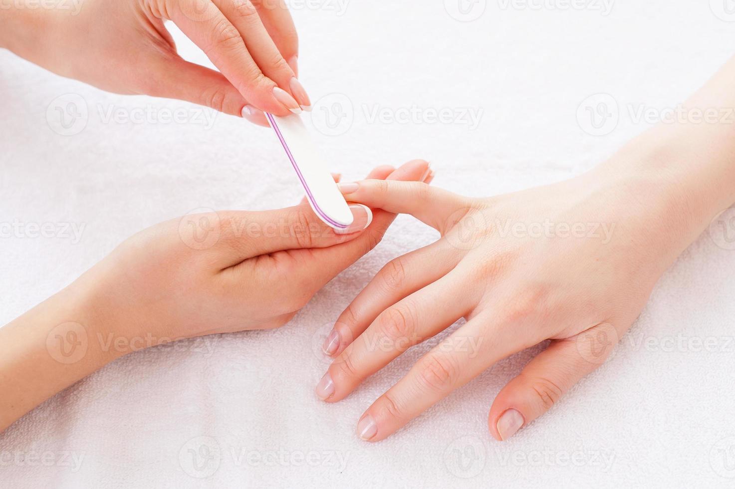 Nail care. Close-up of beautician polishing female nails photo