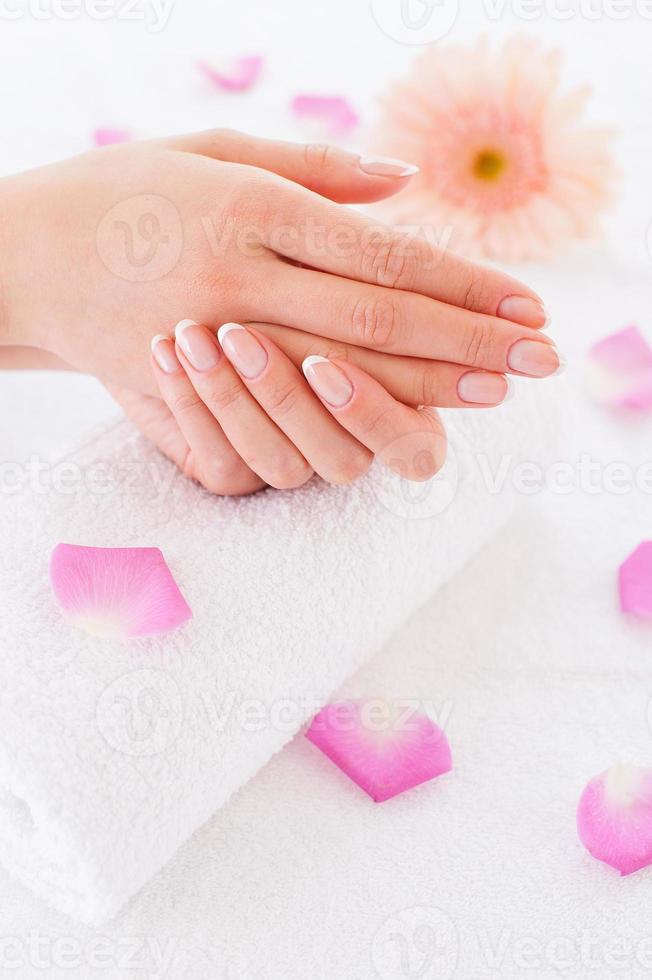 So clean and smooth. Close-up of beautiful female hands on the towel with rose petals laying around photo