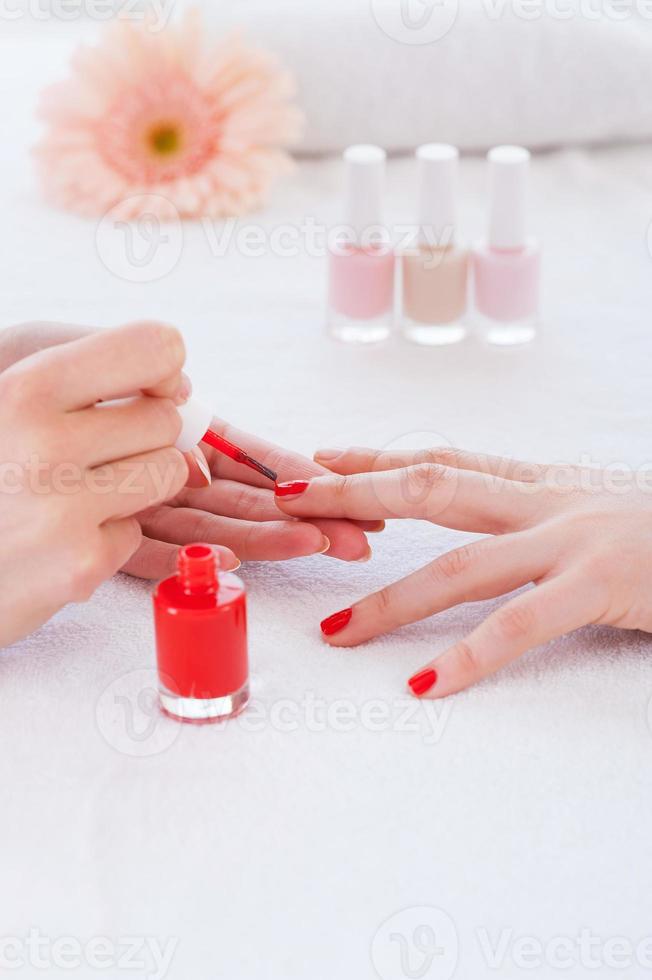 Making red manicure. Close-up of beautician doing red  manicure to female customer photo