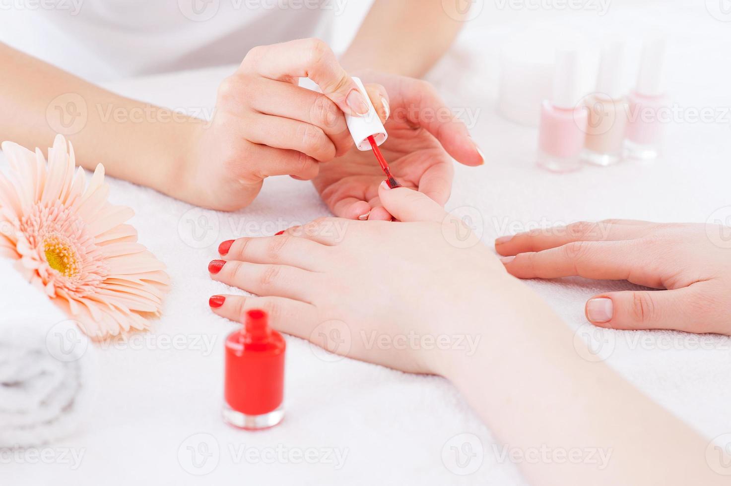 Manicurist in action. Close-up of manicurist doing red manicure to female customer photo