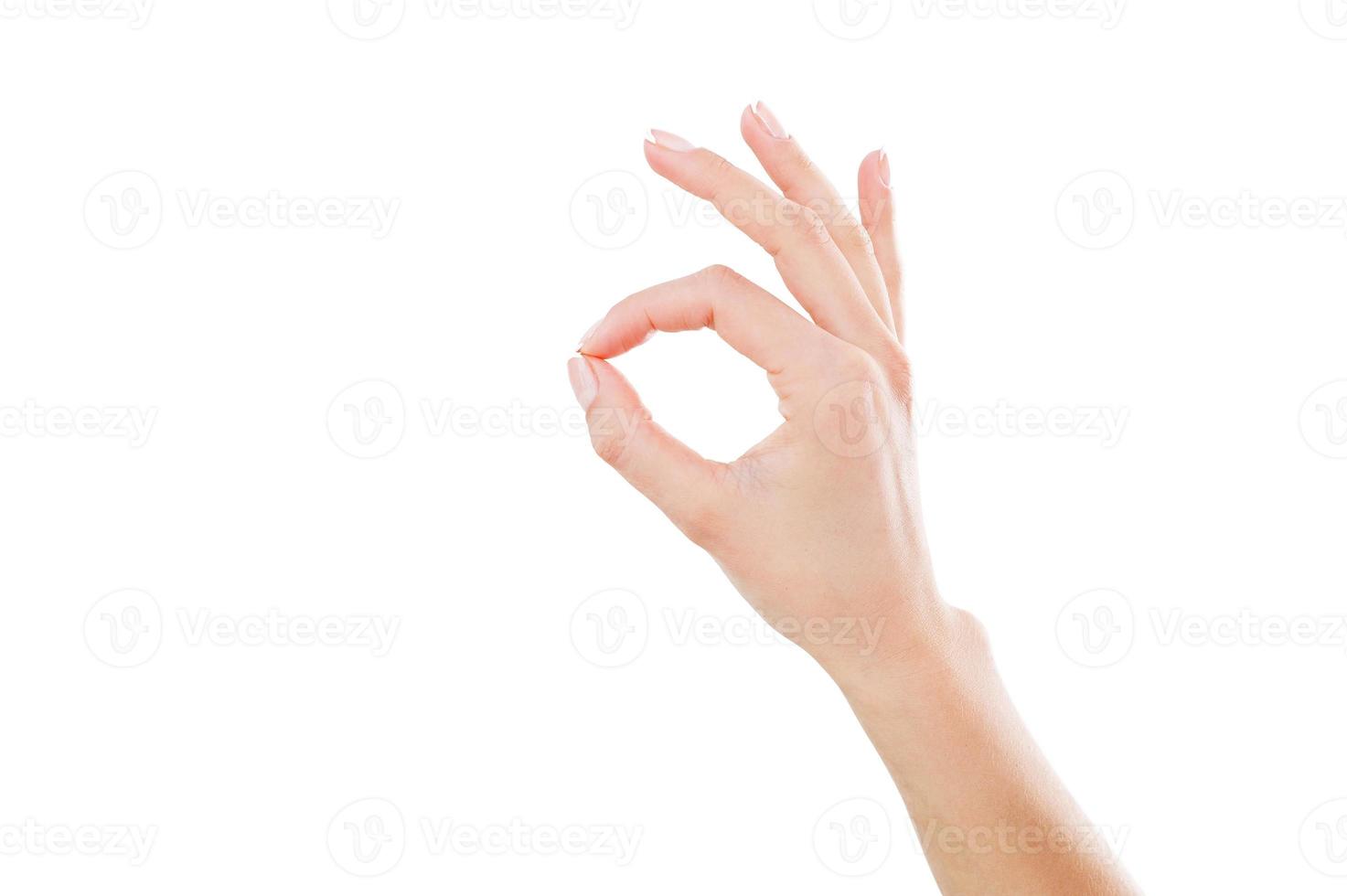 OK sign. Close-up of female hand gesturing OK sign while isolated on white photo