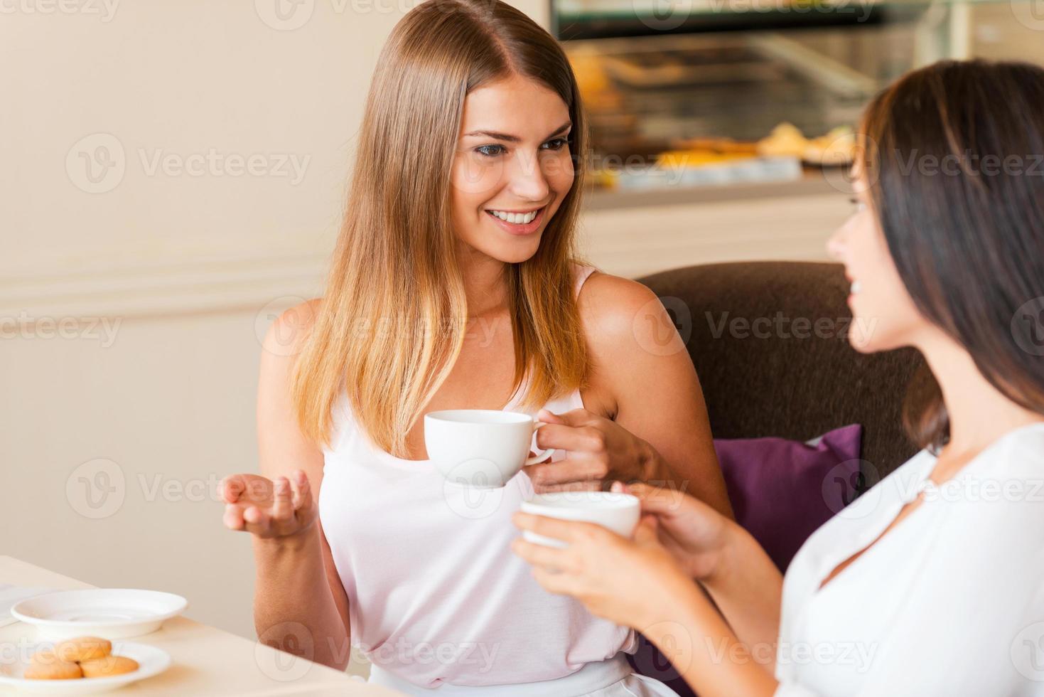 chicas en la cafetería. dos mujeres jóvenes atractivas tomando café y hablando mientras están sentadas juntas en una cafetería foto