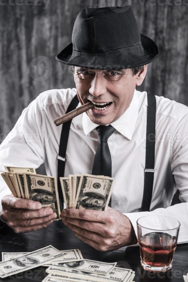 I t is all mine Senior gangster in shirt and suspenders counting money and  looking at you with smile while sitting at the table 13308721 Stock Photo  at Vecteezy