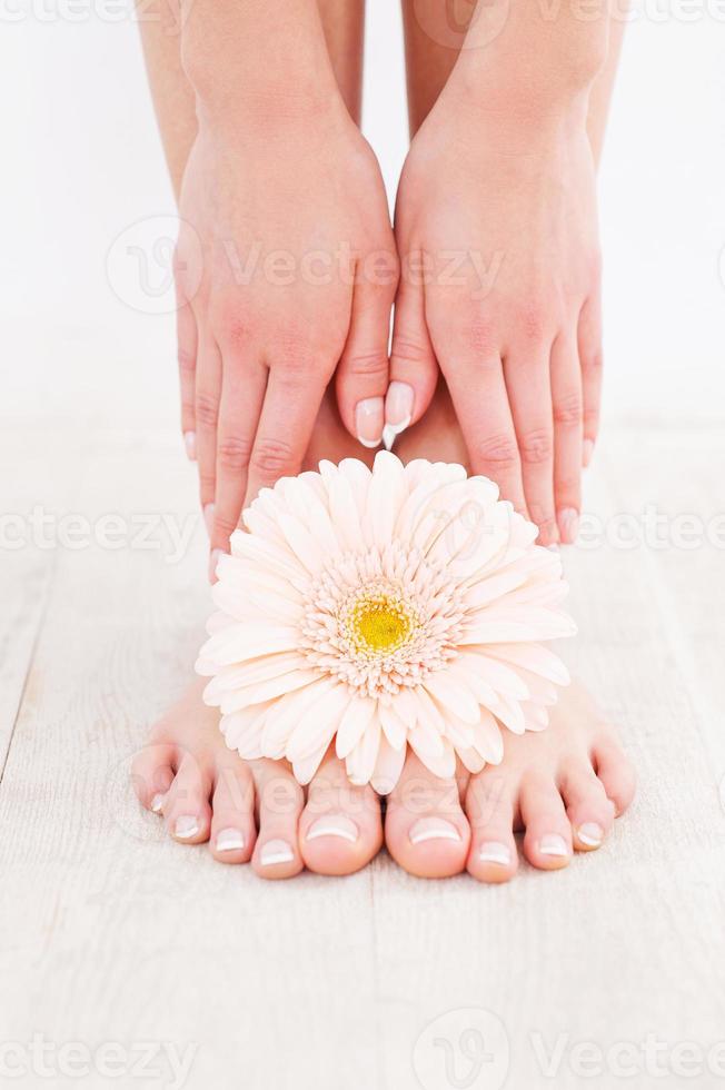 Beautiful feet. Close-up of young woman touching her feet while standing on hardwood floor photo