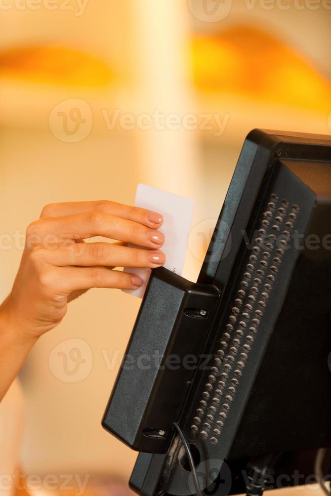 Cashier at work. Close-up of female cashier swipes a plastic card through a machine photo