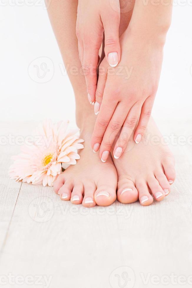 manteniendo sus pies limpios y suaves. primer plano de mujer tocando sus pies mientras está de pie en el piso de madera dura foto