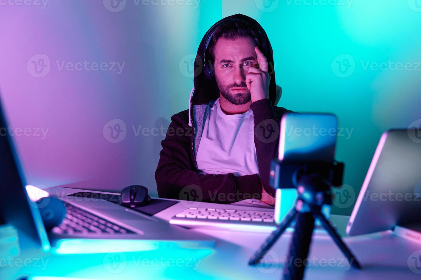 Confident young man looking at camera during live stream against colorful background photo