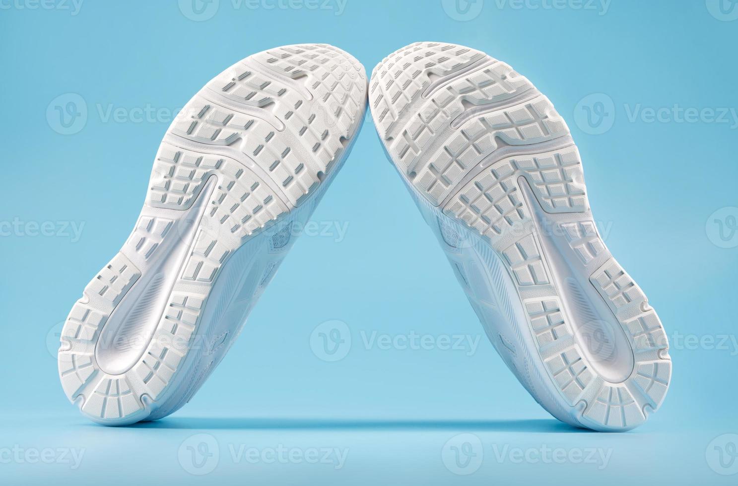 Sporting white sneakers on a blue background. View from the sole side. photo