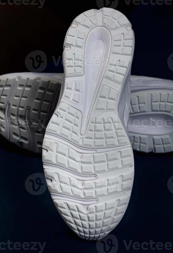 The white sole of sneakers on a dark blue background. A couple of white sneakers. photo
