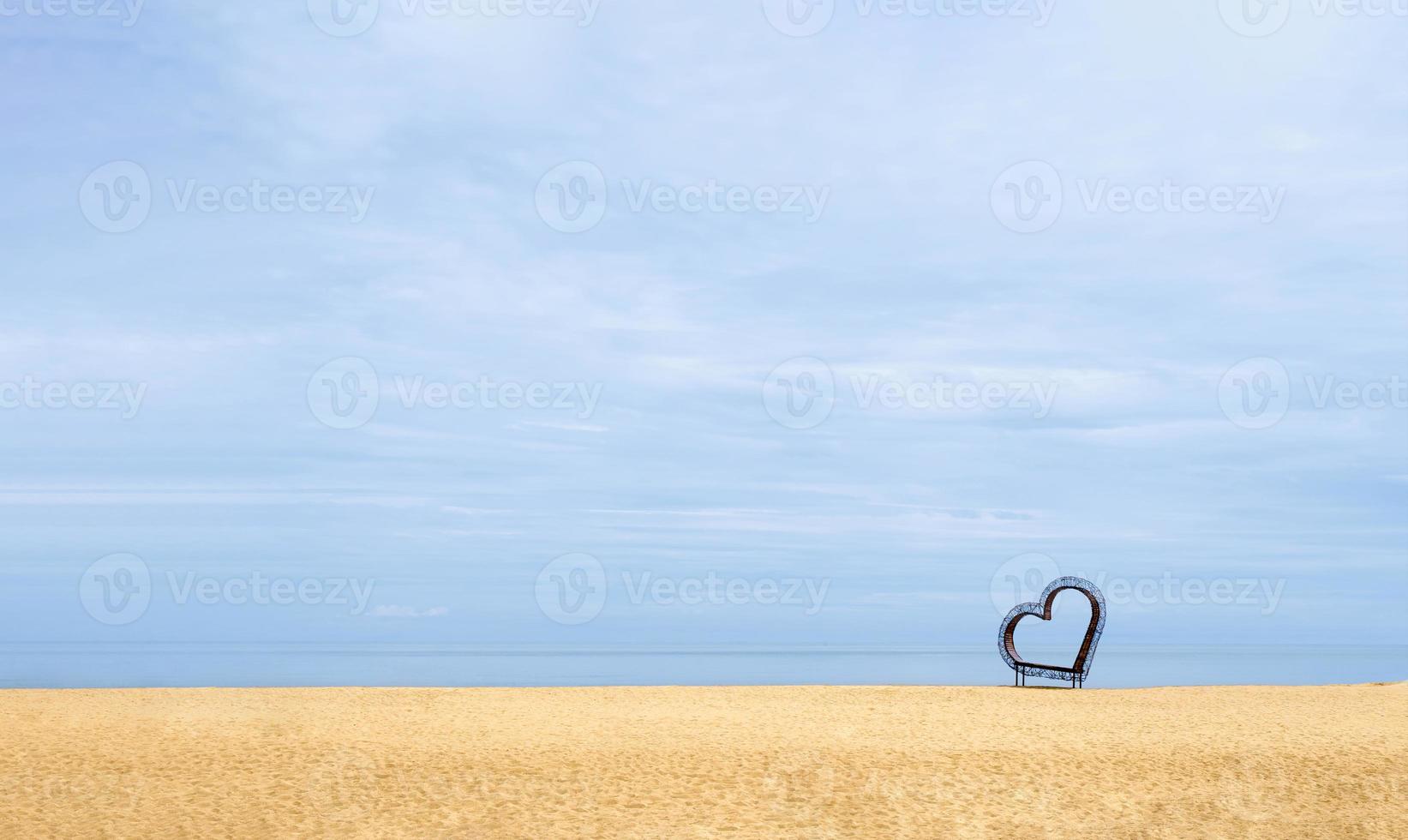 corazón en la playa de arena junto al mar con un cielo azul claro, un marco de corazón en la arena marrón de una playa tropical con un océano azul claro en la isla en verano soleado, símbolo romántico para la tarjeta de San Valentín o la boda foto