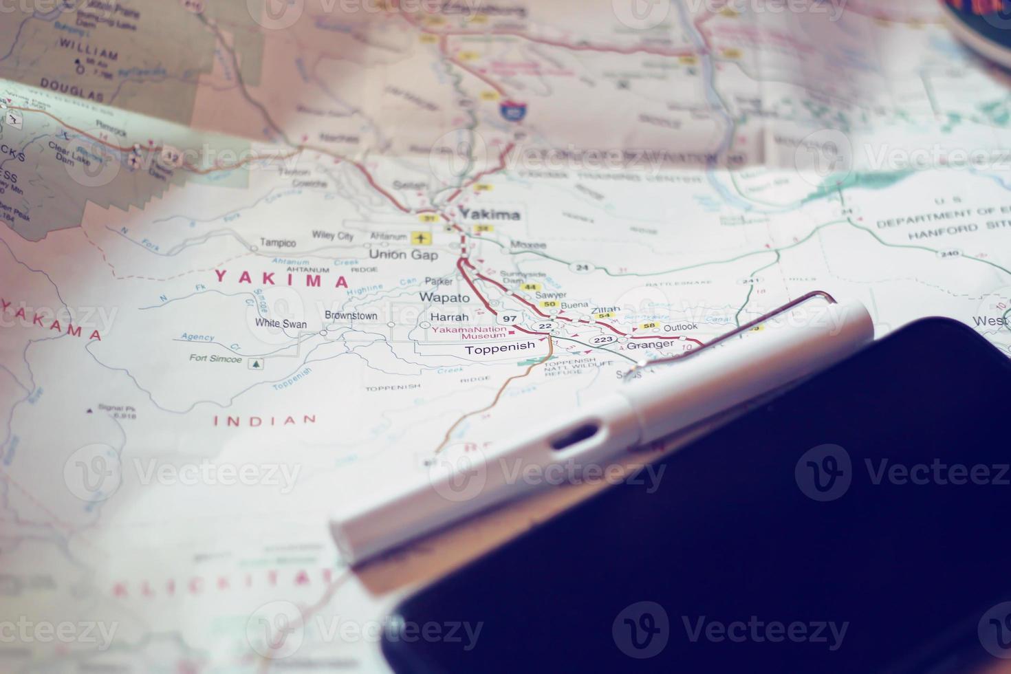 Map, map of Washington state, pen, glasses, cell phone, coffee cup on the table. photo