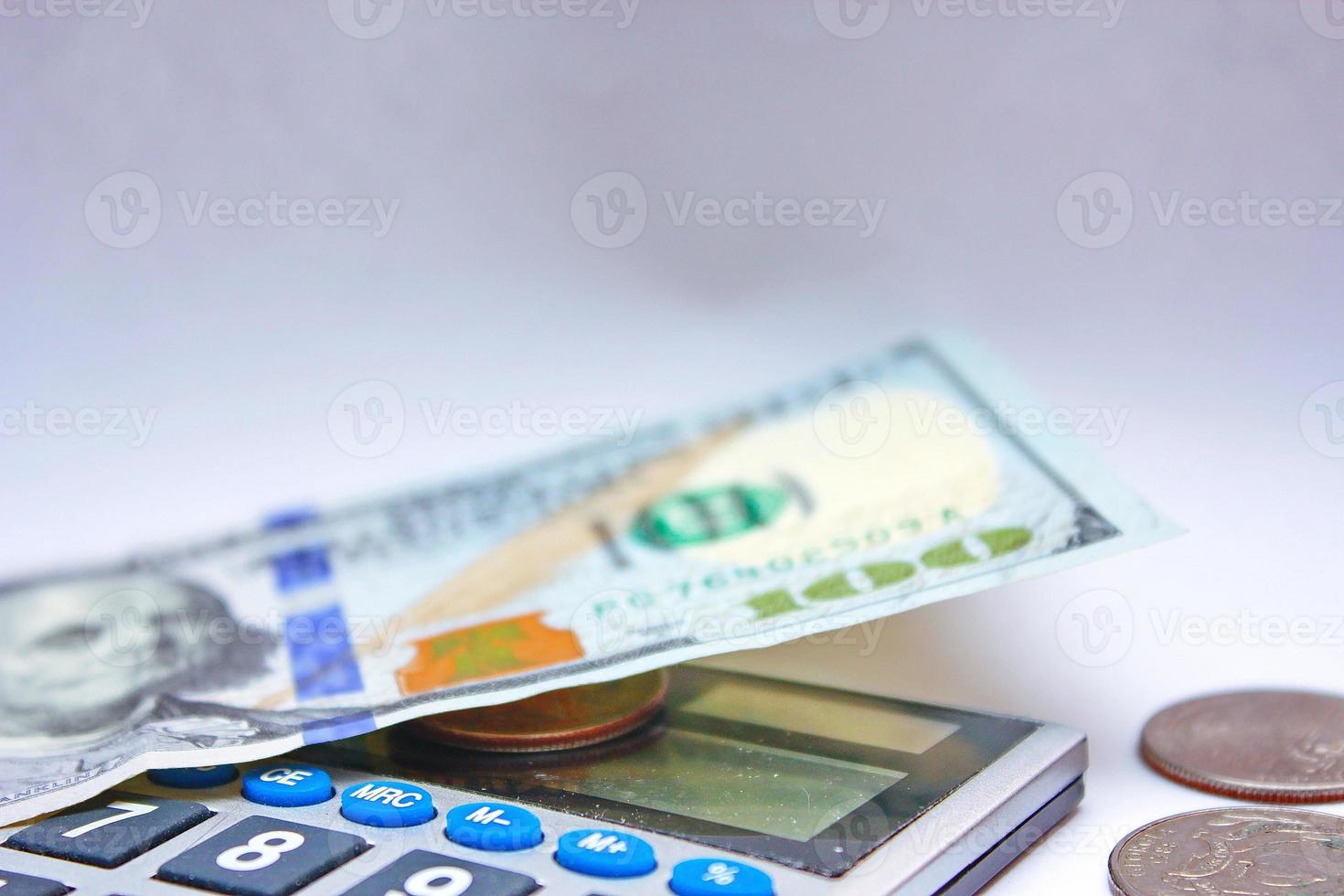 Calculator and dollar bills are placed on a white table. photo