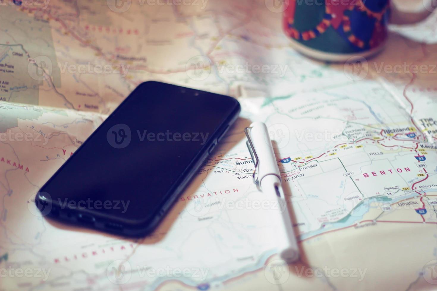 Map, map of Washington state, pen, glasses, cell phone, coffee cup on the table. photo