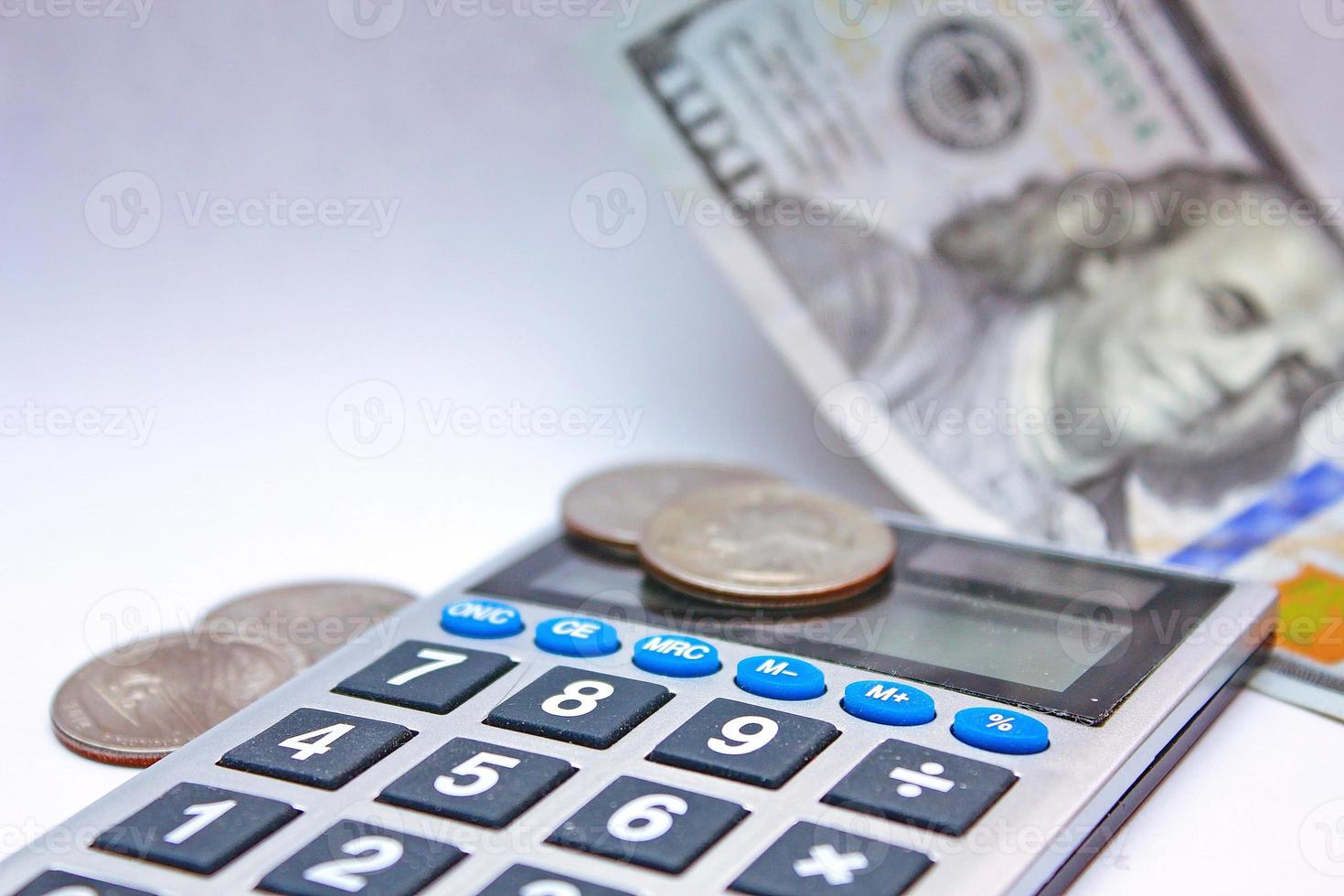 la calculadora y los billetes de dólar se colocan sobre una mesa blanca. foto