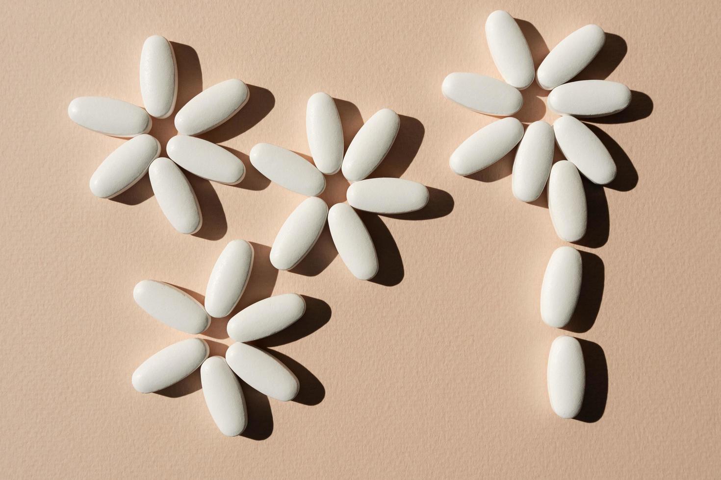 Tablets, vitamins on a light pink background, flowers from tablets, a minimalist concept photo