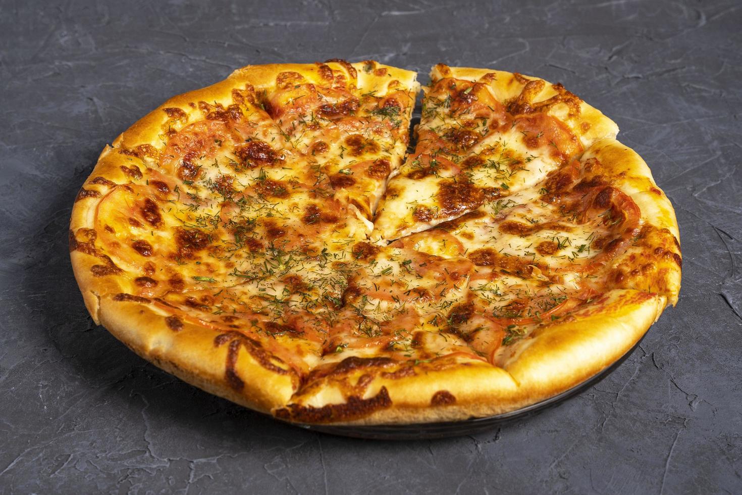 Delicious warm pizza on a gray-black background. Top-side view of delicious baked hot pizza photo