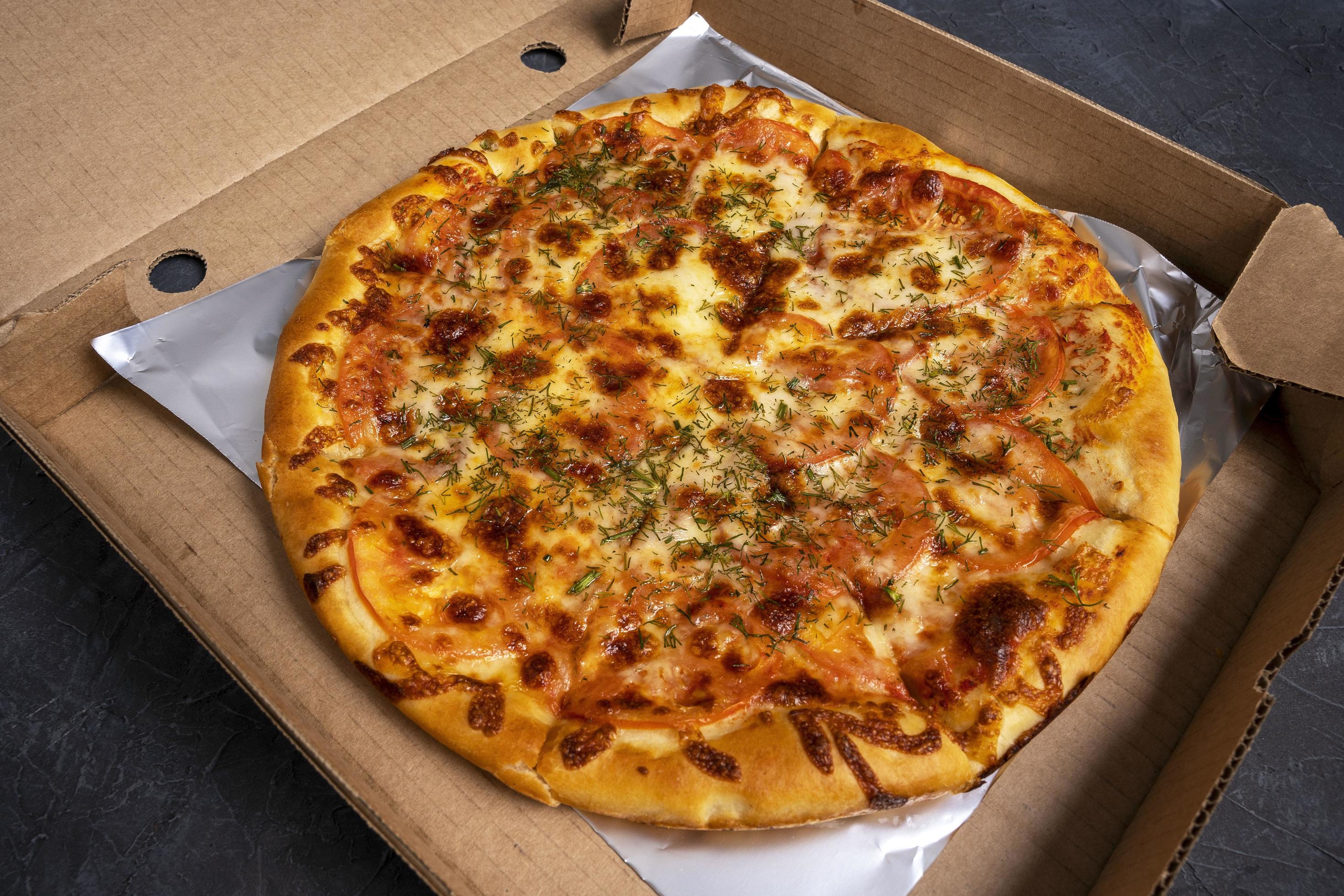 Hot pizza delivery. Delicious pizza in a cardboard box with foil on a