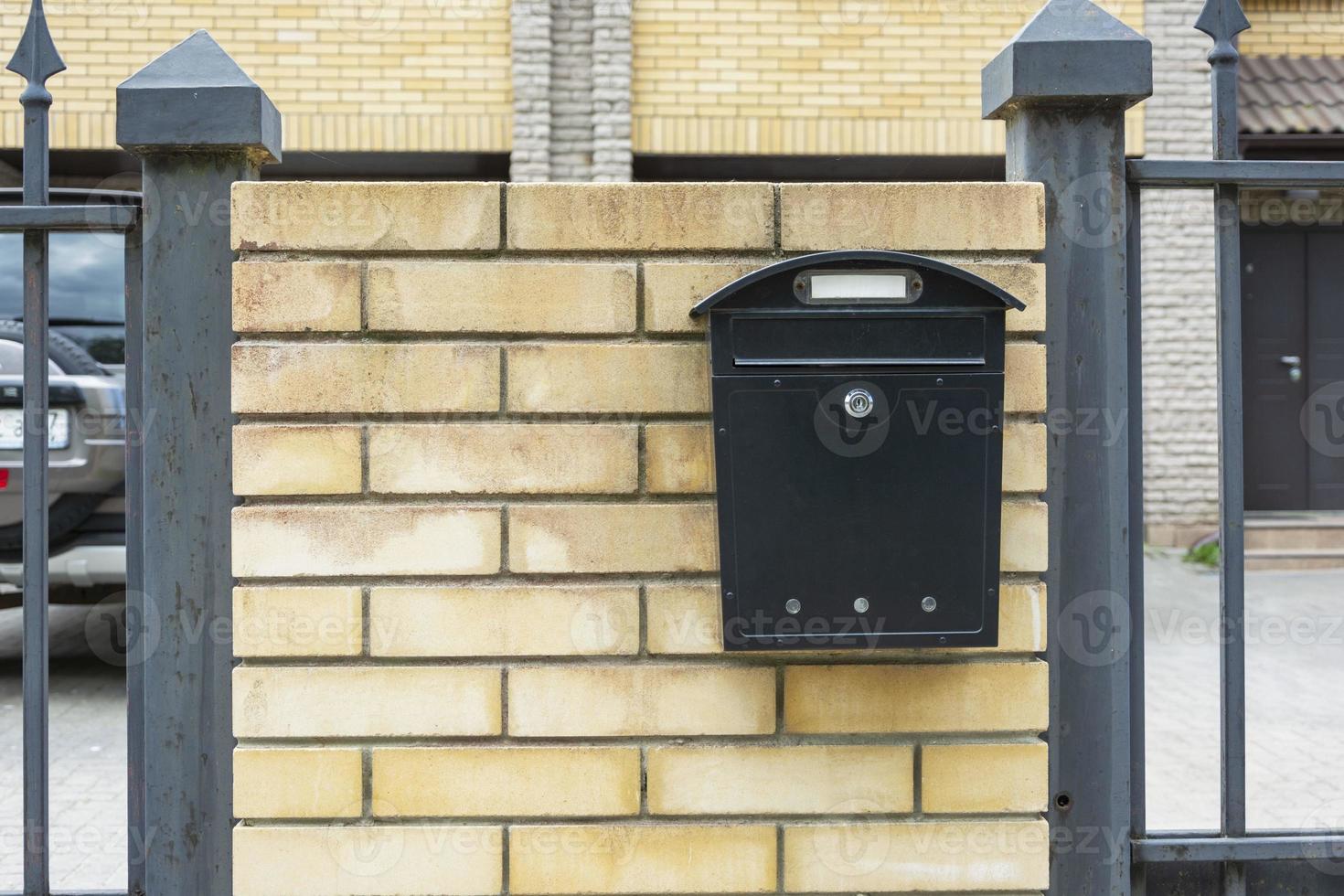Mailbox of a private house, a mailbox made of black metal installed on a brick fence of a private residential house photo