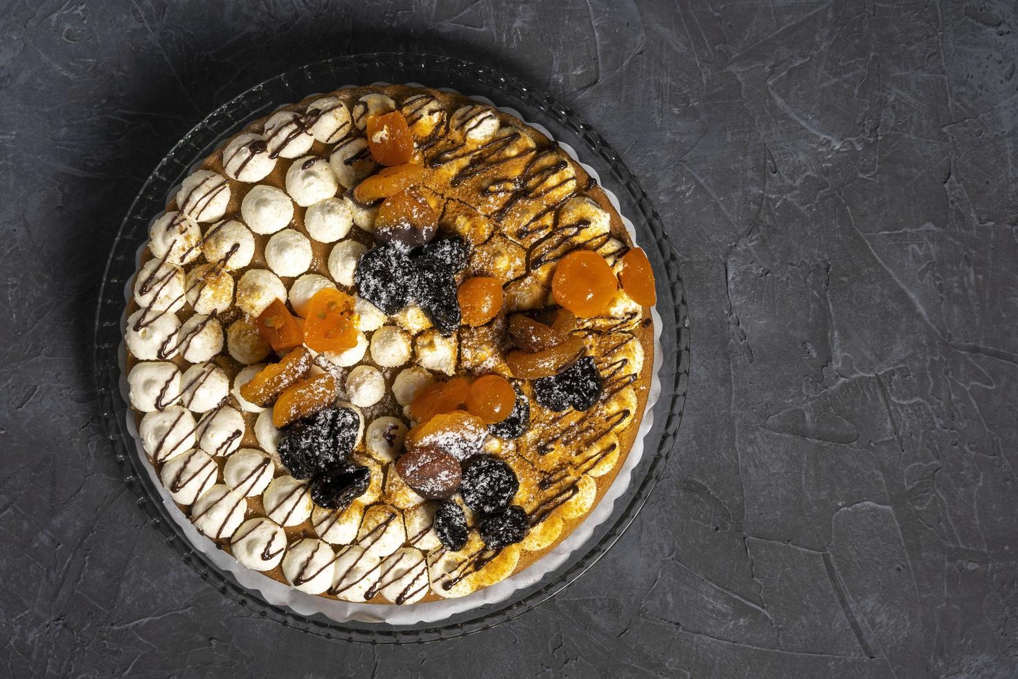 Delicious big fresh beautiful round cream cake decorated with prunes, dried apricots and chocolate photo