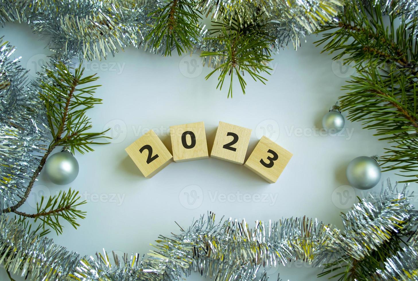 Cubes with the inscription 2023, Christmas tree branches, tinsel and Christmas balls. photo