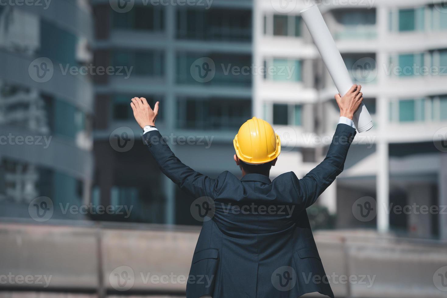 Architecture Engineer raised hands and holding blueprint to showing success building site. photo