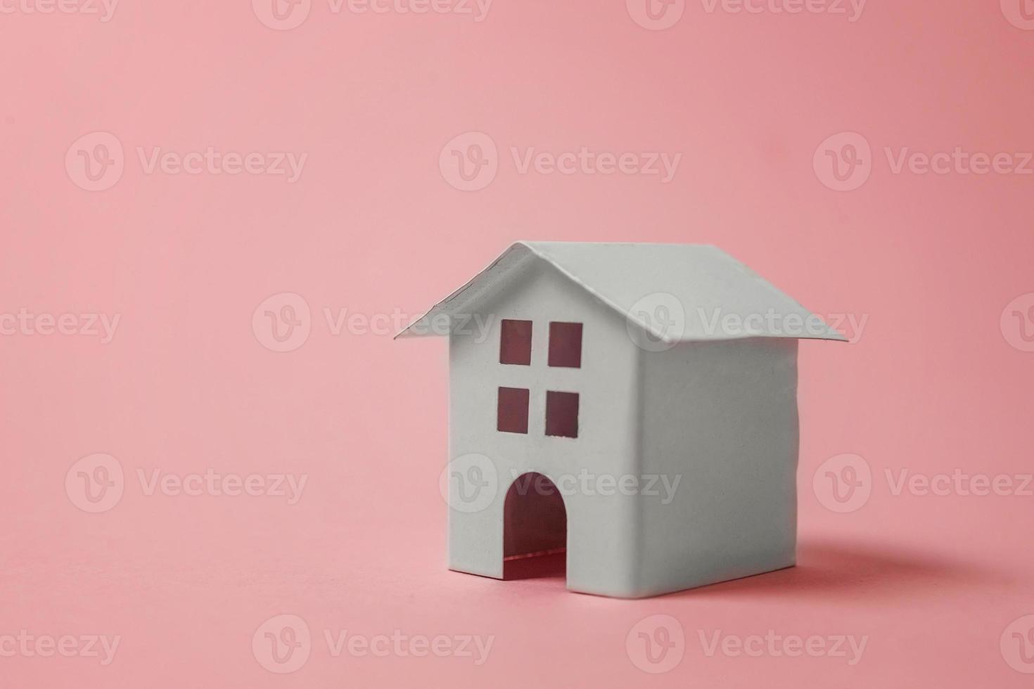 Simply design with miniature white toy house isolated on pink pastel colourful trendy background. Mortgage property insurance dream home concept. Copy space. photo