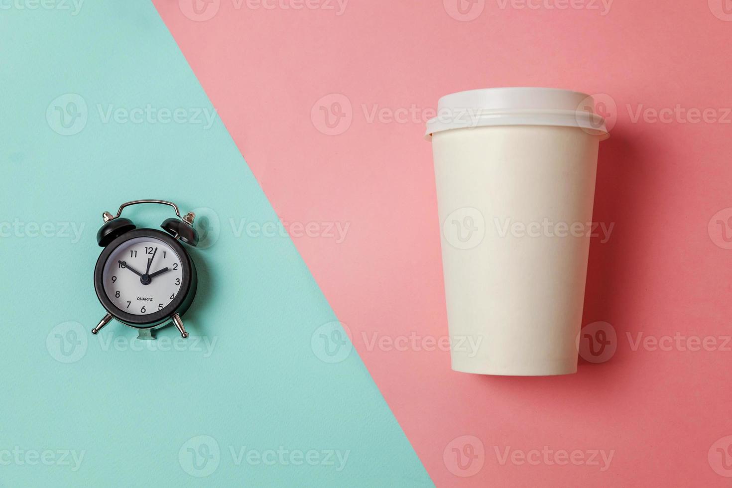 Simply flat lay design paper coffee cup and alarm clock on blue pink pastel colorful trendy background. Takeaway drink and breakfast beverage. Good morning wake up awake concept. Top view copy space. photo