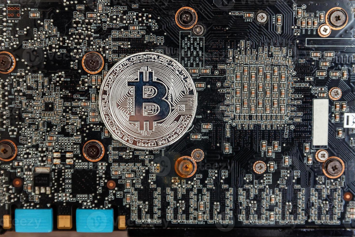 Cryptocurrency silver bitcoin coin lying on video card. Electronic virtual money for web banking and international network payment. Symbol of crypto virtual currency. Mining concept. photo