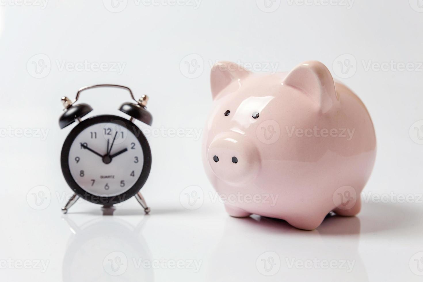 Pink piggy bank and classic alarm clock isolated on white background. Saving time investment budget wealth business retirement, financial, money, banking concept. Copy space. photo