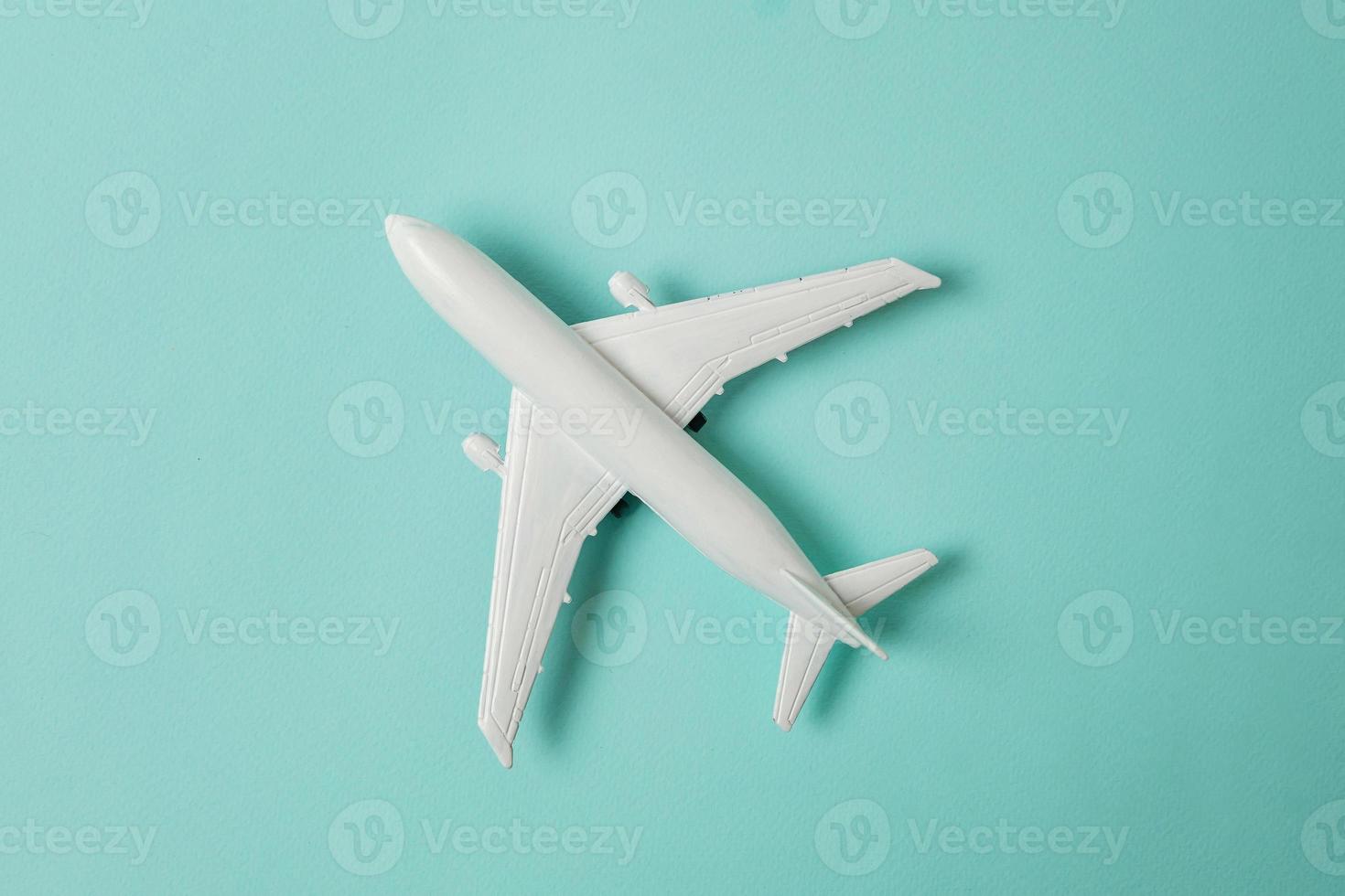 Simply flat lay design miniature toy model plane on blue pastel colorful paper trendy background. Travel by plane vacation summer weekend sea adventure trip journey ticket tour concept. photo