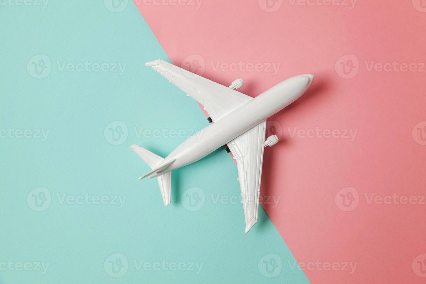 modelo de juguete en miniatura de diseño simplemente plano sobre fondo geométrico de moda de papel de colores pastel azul y rosa. viaje en avión vacaciones verano fin de semana aventura en el mar concepto de viaje. foto
