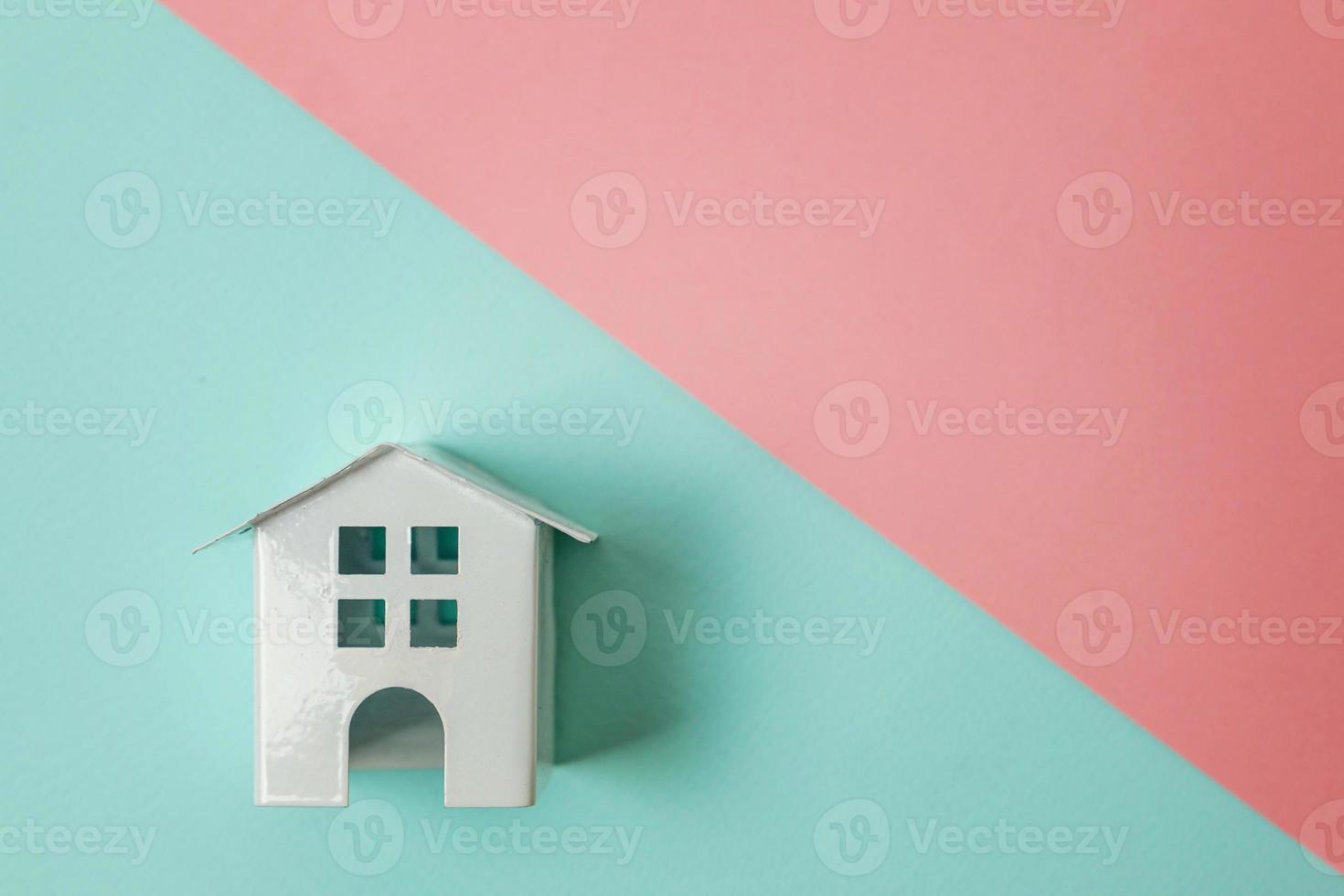 Simply design with miniature white toy house isolated on blue pink pastel colorful trendy geometric background. Mortgage property insurance dream home concept. Flat lay top view copy space. photo