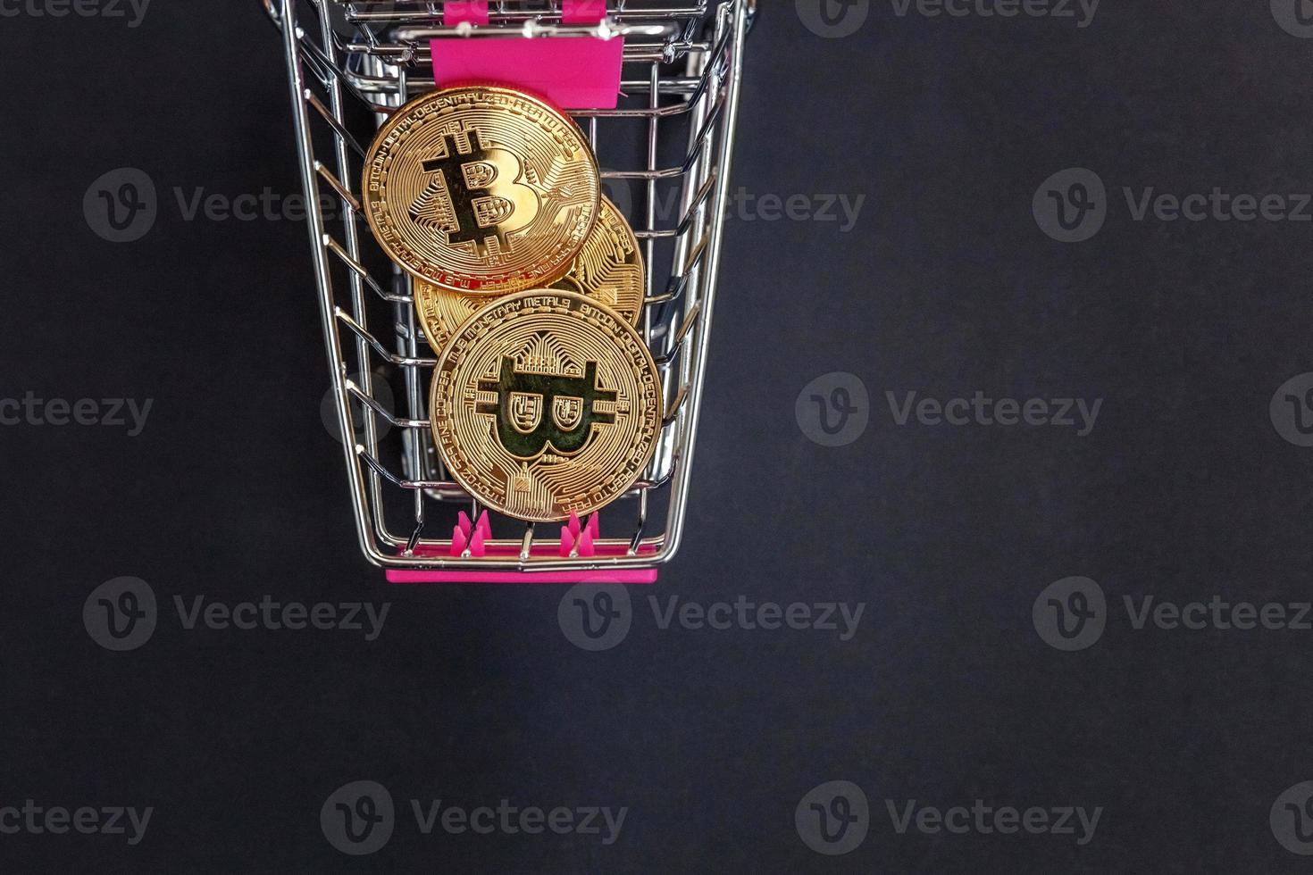 Cryptocurrency golden bitcoin coin in shopping cart on black background. Electronic virtual money for web banking and international network payment. Symbol of crypto virtual currency. Mining concept. photo