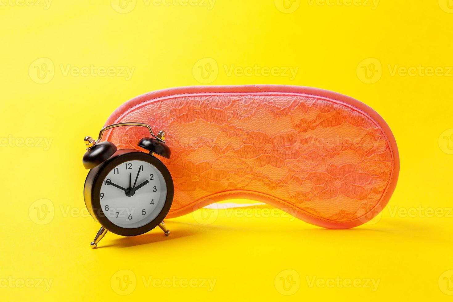 Sleeping eye mask, alarm clock isolated on yellow colourful trendy modern fashion background. Do not disturb me, let me sleep. Rest, good night, siesta, insomnia, relaxation, tired, travel concept. photo