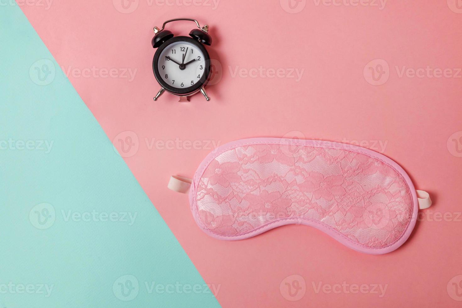 Sleeping eye mask, alarm clock isolated on blue pink pastel colorful trendy geometric background Do not disturb me, let me sleep. Rest, good night, siesta, insomnia, relaxation, tired, travel concept. photo