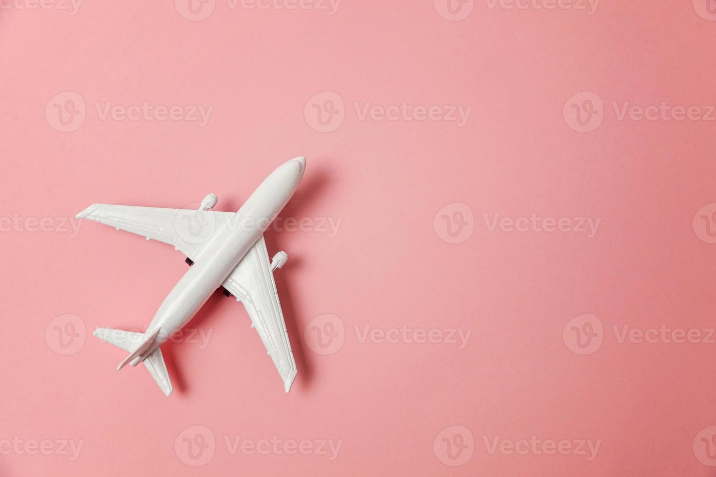 Simply flat lay design miniature toy model plane on pink pastel colorful paper trendy background. Travel by plane vacation summer weekend sea adventure trip journey ticket tour concept. photo