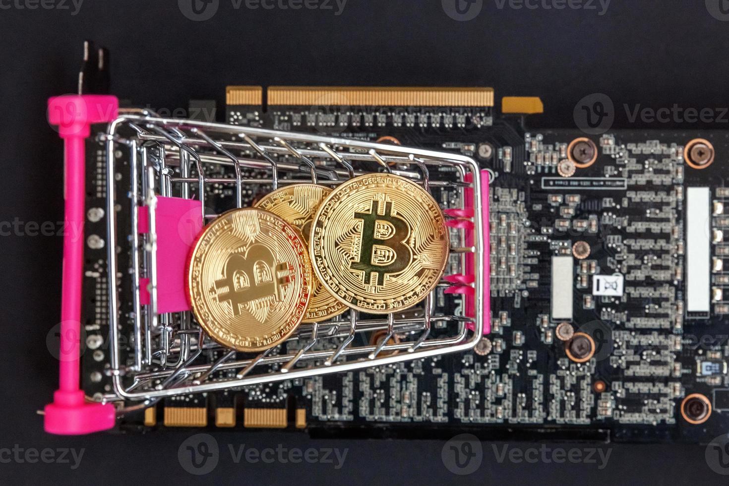 Cryptocurrency golden bitcoin coin lying in shopping cart and video card. Electronic virtual money for web banking and international network payment. Symbol of crypto virtual currency. Mining concept. photo